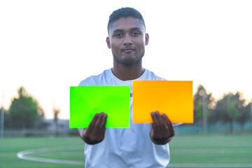 Soccer referee taking out two cards on the field. Front view of soccer referee taking out cards.