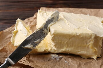 Tasty homemade butter and knife on parchment, closeup