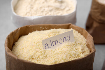 Sack with almond flour on blurred background, closeup