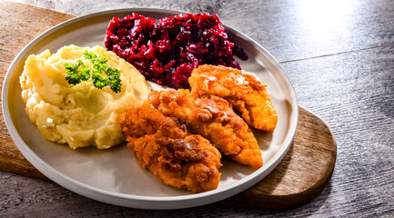 Breaded chicken cutlets served with potatoes and beetroot