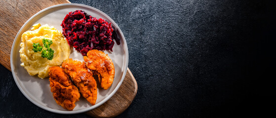 Breaded chicken cutlets served with potatoes and beetroot
