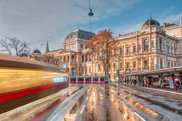 Fototapeta premium View of the University of Vienna (Universitat Wien) with long exposure of a tram - Vienna, Austria