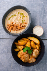 Lunch mushroom cream soup and fried fish with chips and sauce. Vertical orientation, top view.