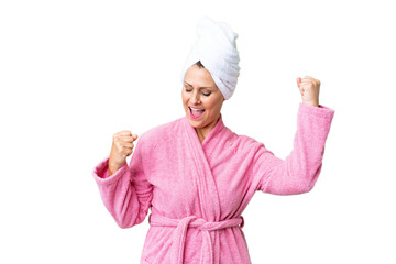 Middle age caucasian woman in a bathrobe over isolated background celebrating a victory