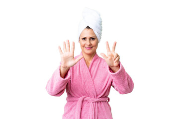 Middle age caucasian woman in a bathrobe over isolated background counting eight with fingers