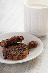 Chocolate cookies and a mug with milk on a wooden table.