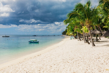 Beautiful view of the tropical beach in Mauritius. Transparent ocean, sand beach, palms and boats