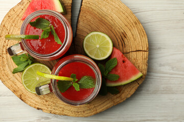 Tasty summer watermelon drink, limes and mint on white wooden table, top view