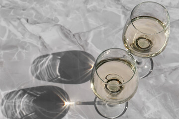 Glasses of white wine served on grey marble table, above view. Space for text