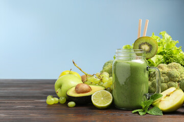 Green smoothie in mason jar and fresh ingredients on wooden table. Space for text