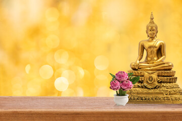 Buddha on wood floor and on golden bokeh background.