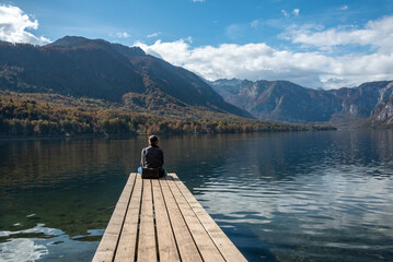 Sitting on a small jetty and enjoying the view on the landscape of lake Bohinj in the Triglav...
