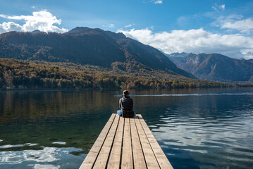 Sitting on a small jetty and enjoying the view on the landscape of lake Bohinj in the Triglav National Park, The Julian Alps of Slovenia