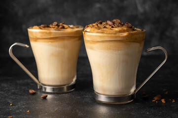Dalgona coffee in glass cups with coffee beans. Dark moody backgroung with copy space