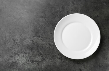 Clean white plate on grey table, top view. Space for text