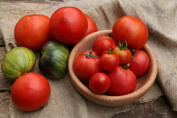 Many different ripe tomatoes on wooden table