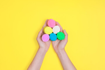 Top view on female hands hold colored modeling clay isolated on yellow background. DIY concept.