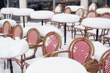 Cafe tables covered with snow, Snowy winter scene on beautiful city street, Outdoor restaurant terrace at cold snowy day