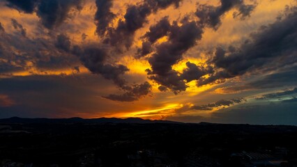 Mesmerizing flaming sunset behind the fluffy clouds in the sky