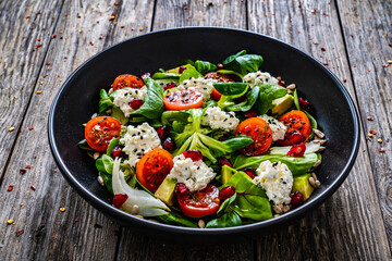 Fresh vegetable salad with feta cheese and pomegranate  on wooden table
