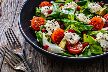 Fresh vegetable salad with feta cheese and pomegranate  on wooden table
