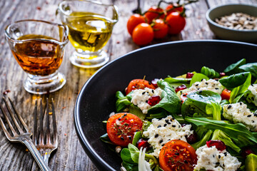 Fresh vegetable salad with feta cheese and pomegranate  on wooden table
