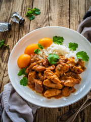 Fried chicken nuggets in peach sauce with white rice on wooden table
