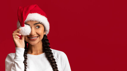 Xmas Ad. Cheerful Arab Lady In Santa Hat Covering Eye With Pompom