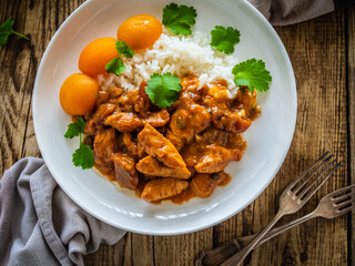 Fried chicken nuggets in peach sauce with white rice on wooden table
