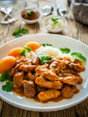 Fried chicken nuggets in peach sauce with white rice on wooden table
