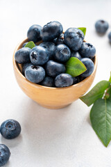 Blueberries berry in wooden bowl, on bright background. Healthy food template, mockup with copy space.