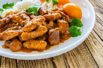 Fried chicken nuggets in peach sauce with white rice on wooden table

