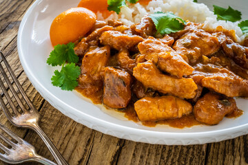 Fried chicken nuggets in peach sauce with white rice on wooden table
