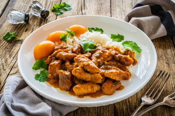 Fried chicken nuggets in peach sauce with white rice on wooden table

