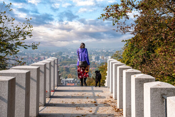 Fototapeta na wymiar A woman walking with her dog in the castle park of Ljubljana, Slovenia