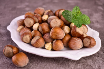 Hazelnuts in a porcelain plate on a gray background. Close-up.
