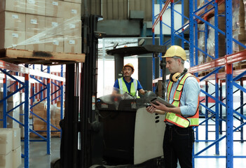 Male warehouse engineer wearing a hard hat Inspecting goods in the warehouse via tablet, radio