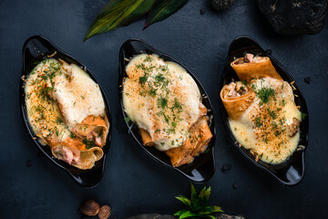 Breakfast thin pancakes with ham, chicken, minced meat, pineapple, onion and cheese sauce in a cast-iron bowls.