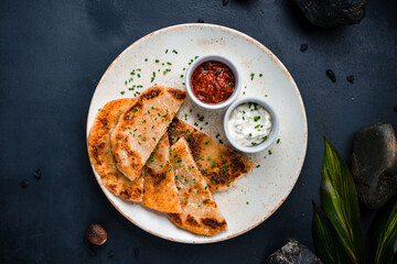 Fried tortillas with sour cream sauce and tomato salsa.