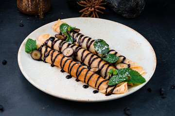 Breakfast sweet thin pancakes with cream cheese, banana, chocolate sauce, blueberries, mint and powdered sugar.