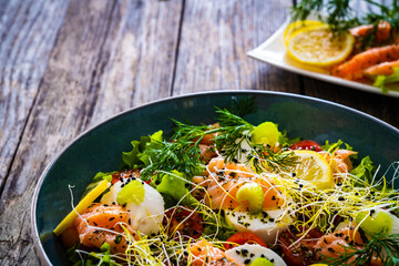 Salmon salad - smoked salmon, goat cheese and fresh vegetables on wooden table
