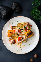 Sliced chicken rolls with baked peppers, mashed potatoes, zucchini slices, corn and herbs.