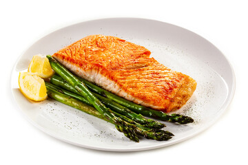 Fried salmon steaks with asparagus and lemon on wooden table
