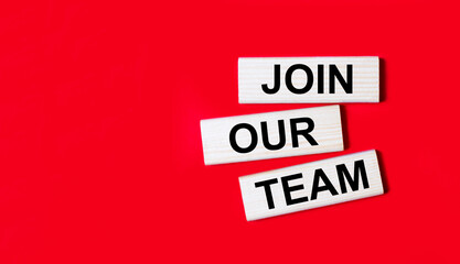 Three wooden blocks with the text JOIN OUR TEAM on a bright red background. Copy space