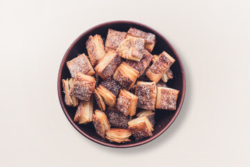 Homemade sweet puff pastry in a ceramic bowl on a light background top view.