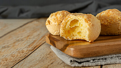 bitten pão de queijo, a traditional brazilian food made of chesse bread, over wooden table and cutting board
