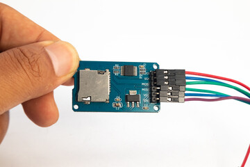 A microSD card reader module with its connecting cable is held in the hand. This module is used for...
