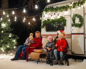 Happy Caucasian family celebrating Christmas outdoors. Parents and three sons travel in a camper. 