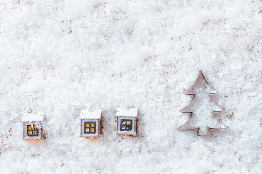 Christmas decoration, small houses and gingerbread cookie cutter on snowy background