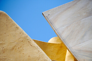 Astronomical Observatory at Jantar Mantar in Jaipur, India. Geometric shapes of architecture isolated against blue sky background. Astronomical calculating instrument measures longitude and latitude.